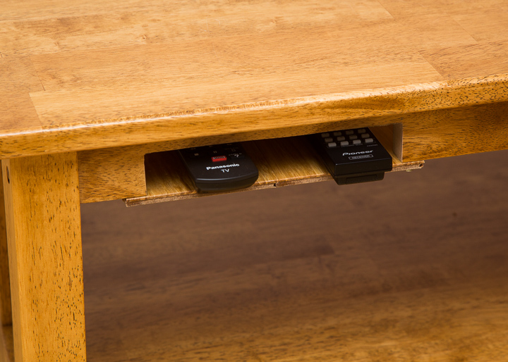 A close-up of one of the cut out on the left side of the coffee table showing two remotes.